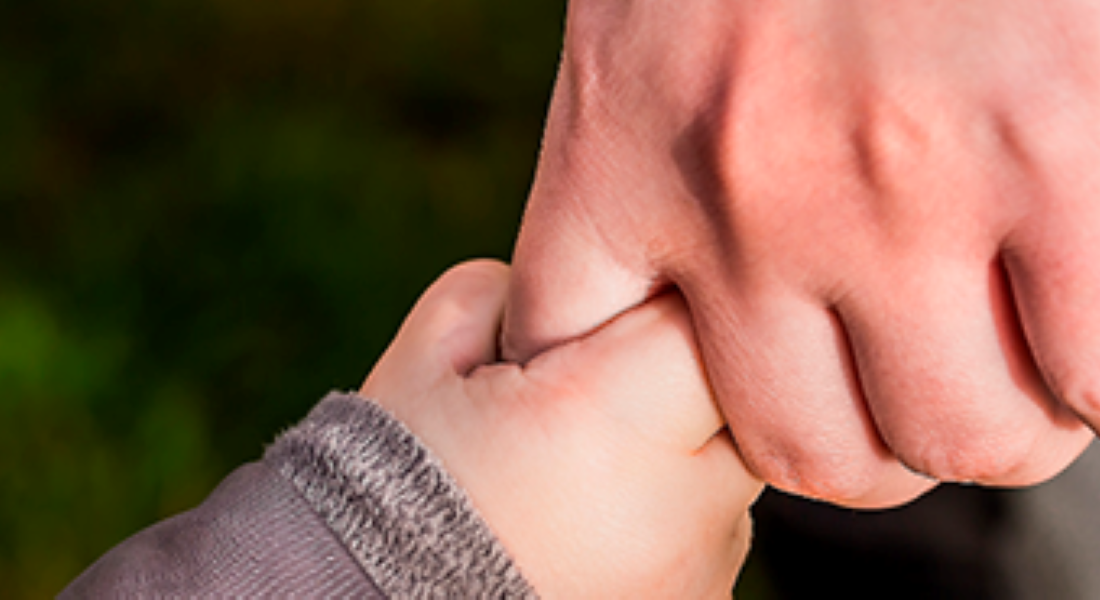 Stemningsbillede af en barnehånd, der holder en voksenhånd. 